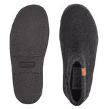 Dois chinelos Green Comfort pretos de feltro de lã, um mostrando a sola de borracha antiderrapante, o outro a parte superior
